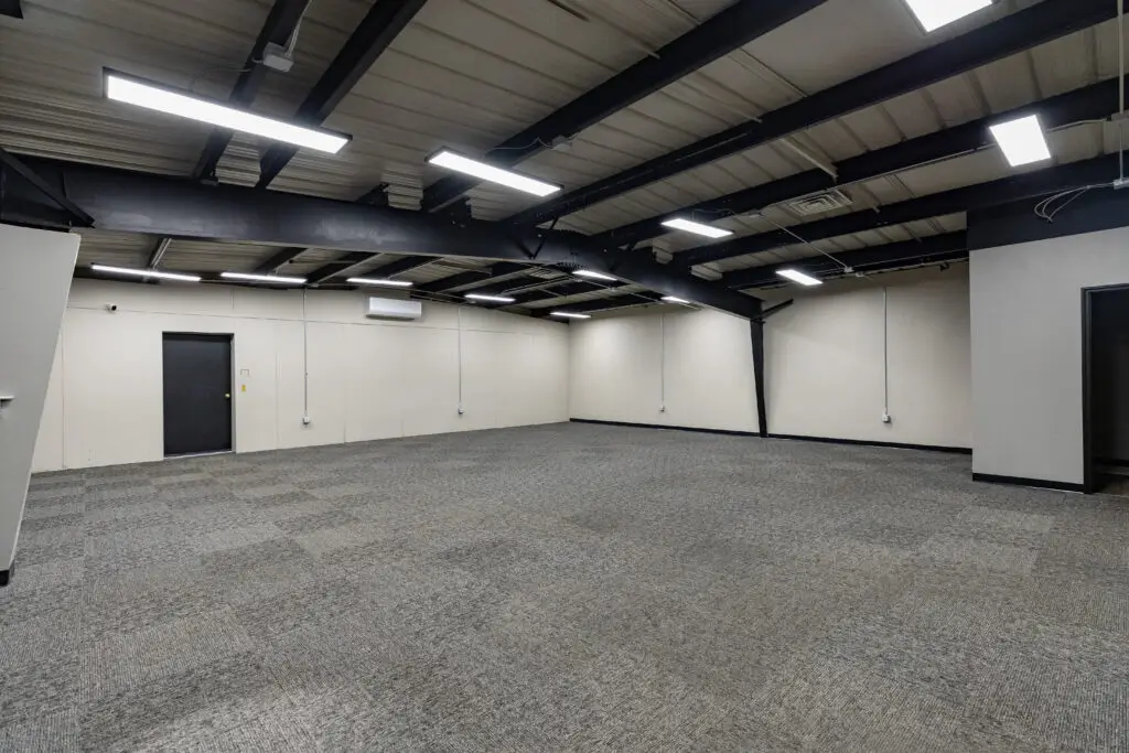 Commercial tile flooring in Fond du Lac - empty commercial space with a black ceiling, light gray walls, and dark gray carpet tile