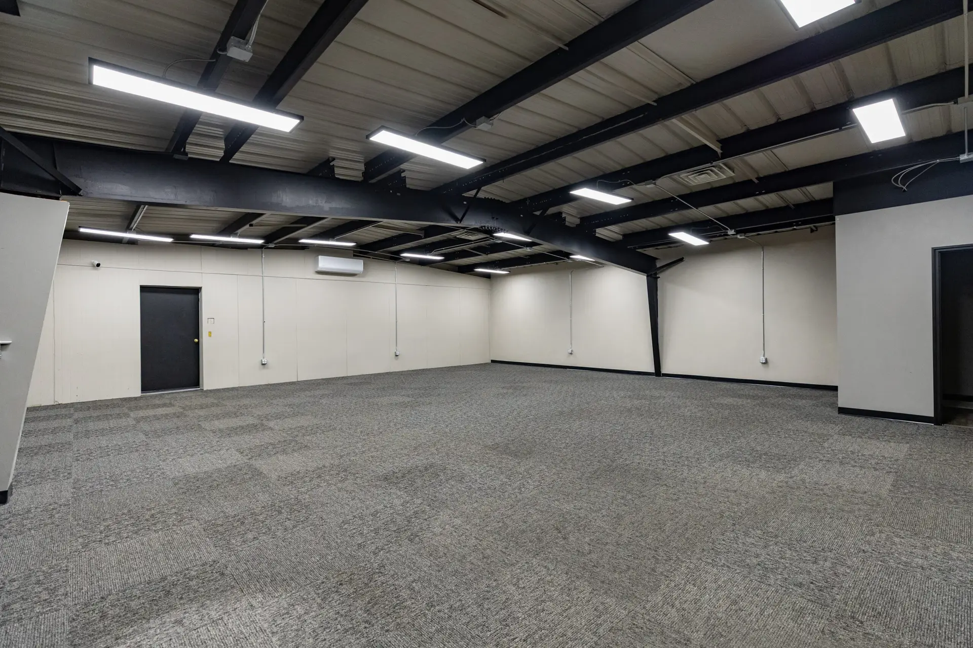 Commercial tile flooring in Fond du Lac - empty commercial space with a black ceiling, light gray walls, and dark gray carpet tile